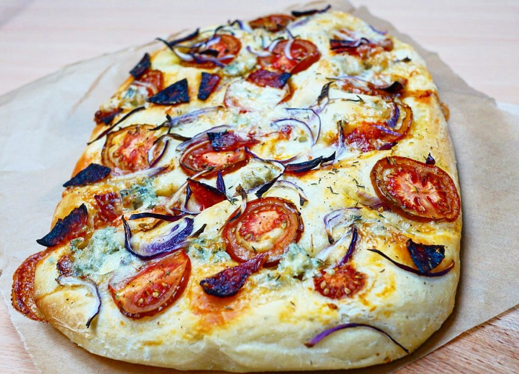 Focaccia au chorizo et gorgonzola, avec des tomates et des oignons rouges