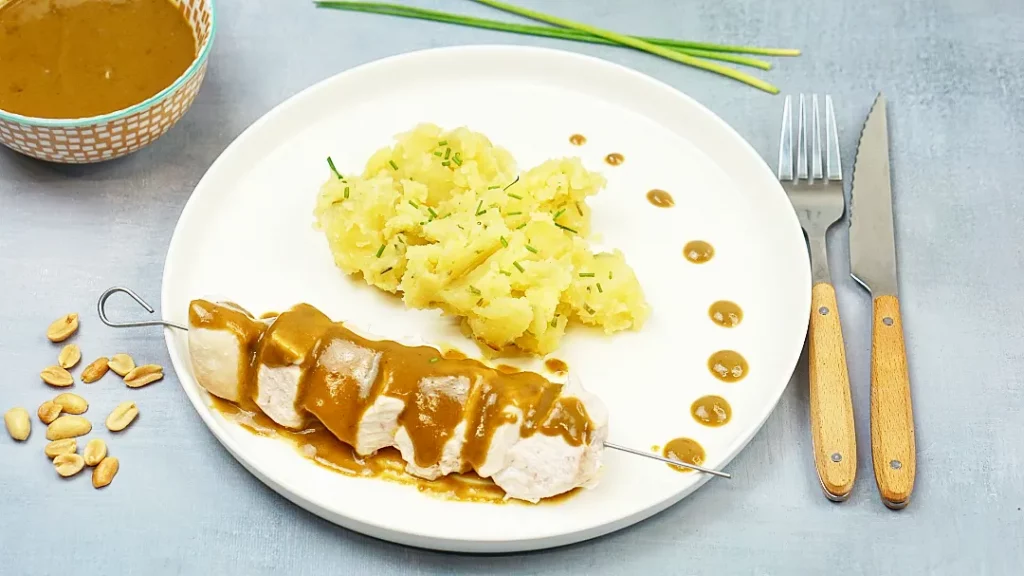 Brochette de poulet au satay et écrasé de pomme de terre aux herbes