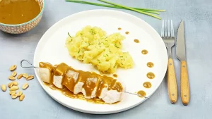 Brochette de poulet au satay et écrasé de pomme de terre aux herbes